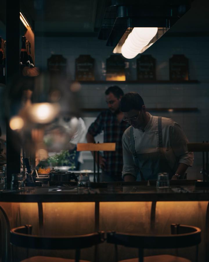 Two members of staff working behind the lit bar counter