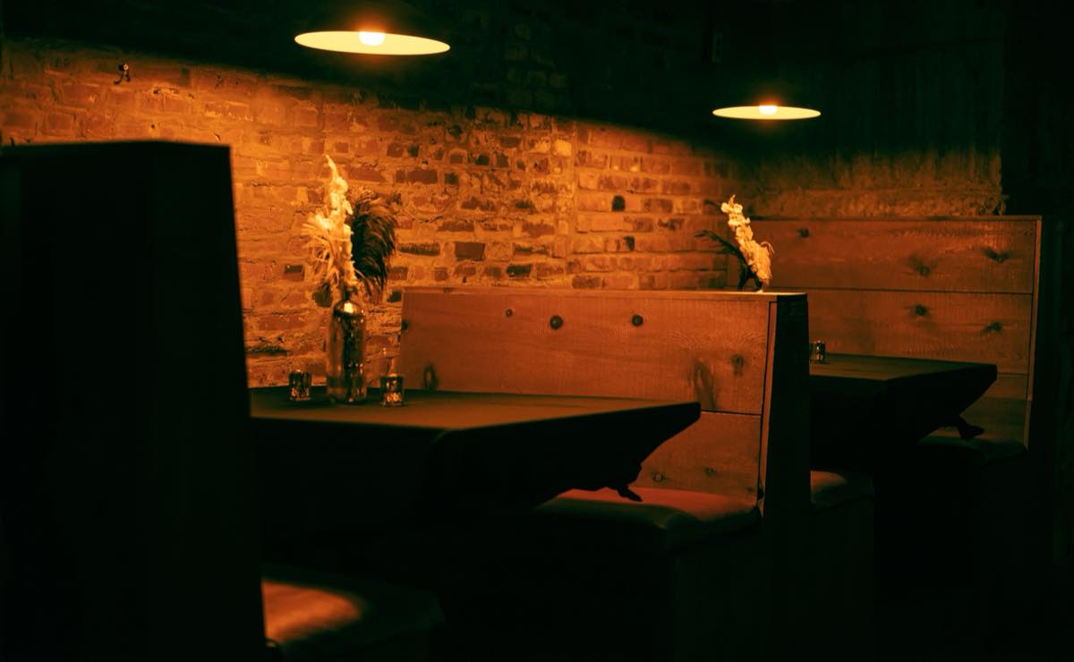 The dining room at night, brick walls lit by low pendant lamps and candles on the tables