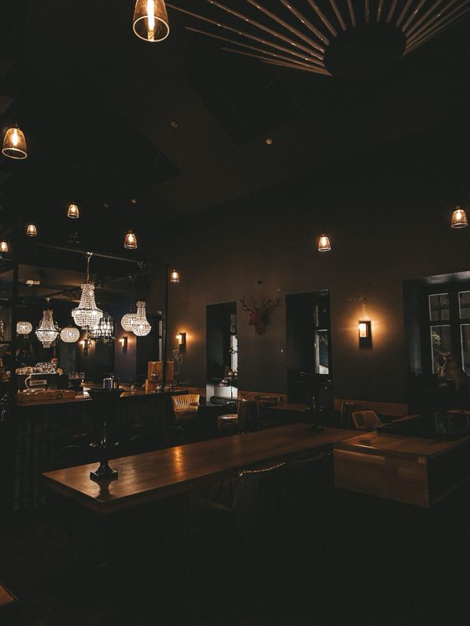 The bar at night, lit by hanging lamps and small chandeliers