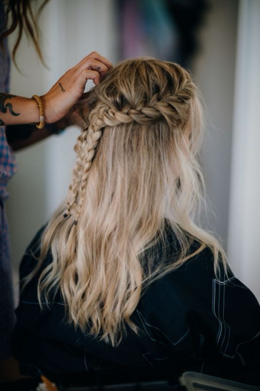 Braided blonde hair being finished by a stylist