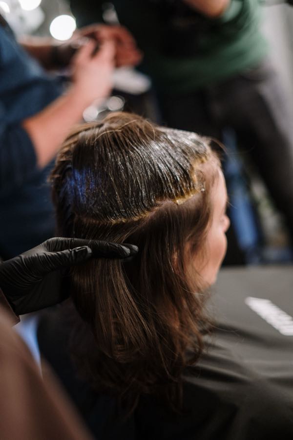 A stylist applying colour to a client's hair with a brush