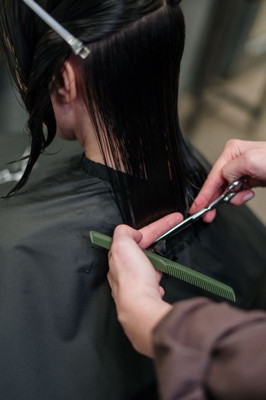 Scissors cutting a section of wet dark hair