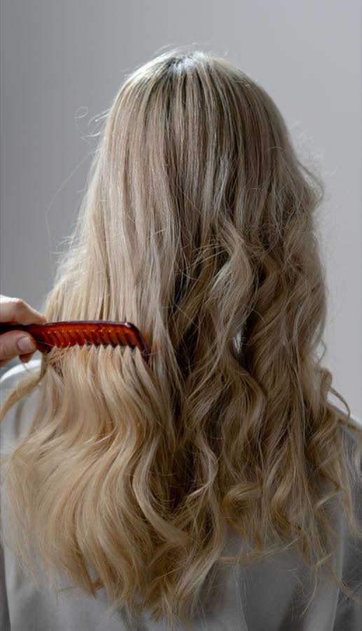Long blonde wavy hair being combed through